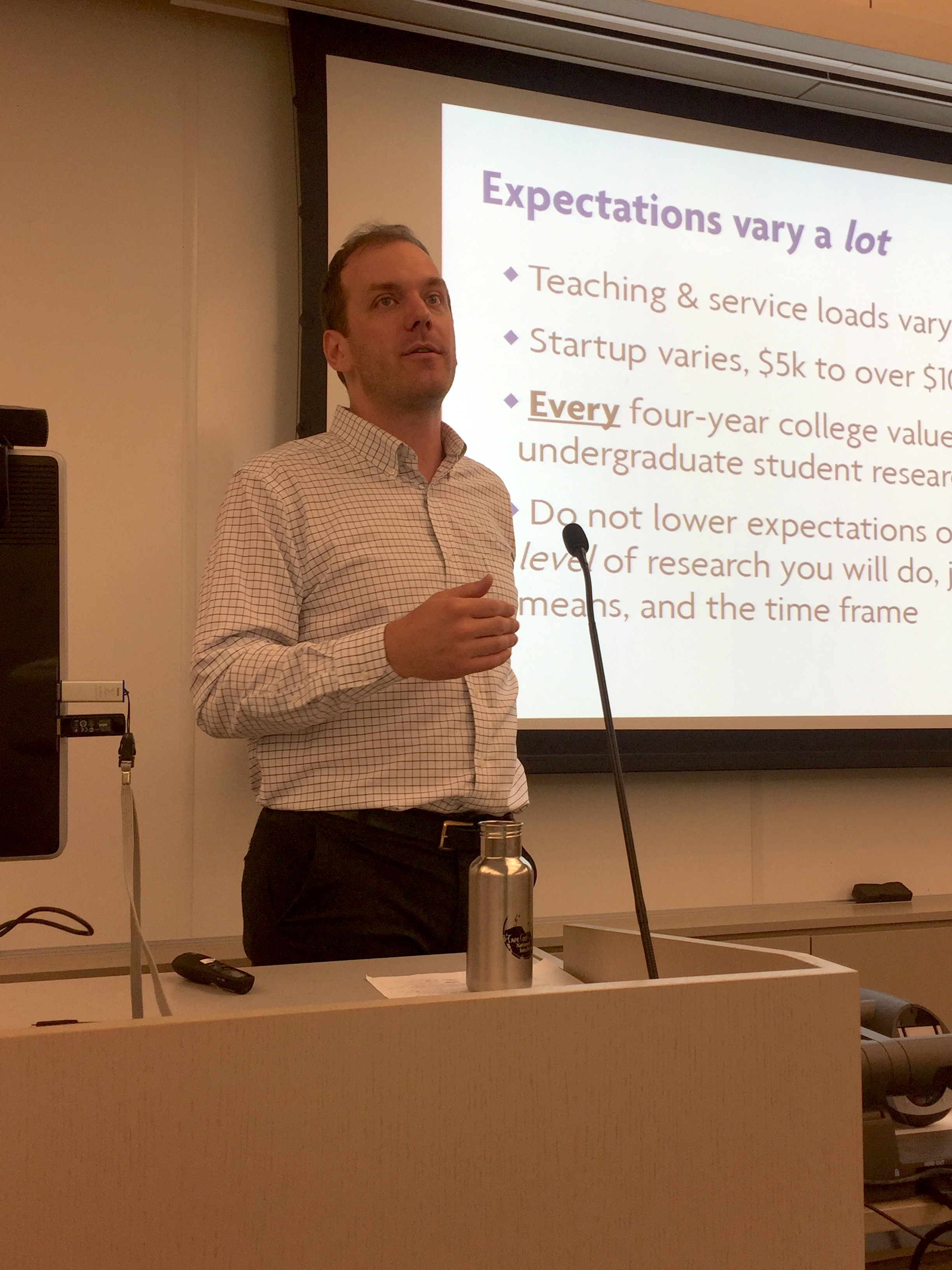 Jeffrey Werner in front of a slide that reads "Expectations vary a lot. Teaching and service load varies. Startup varies. Every four-year college values undergraduate research."