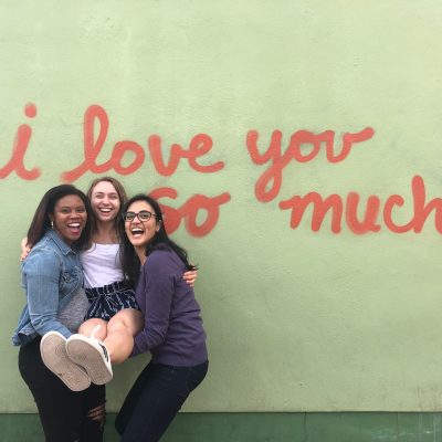 Three students against mural saying, "I love you so much"