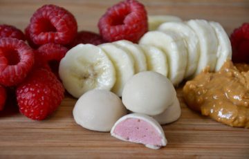 Smoothie Bites surrounded by raspberries, bananas, and peanut butter