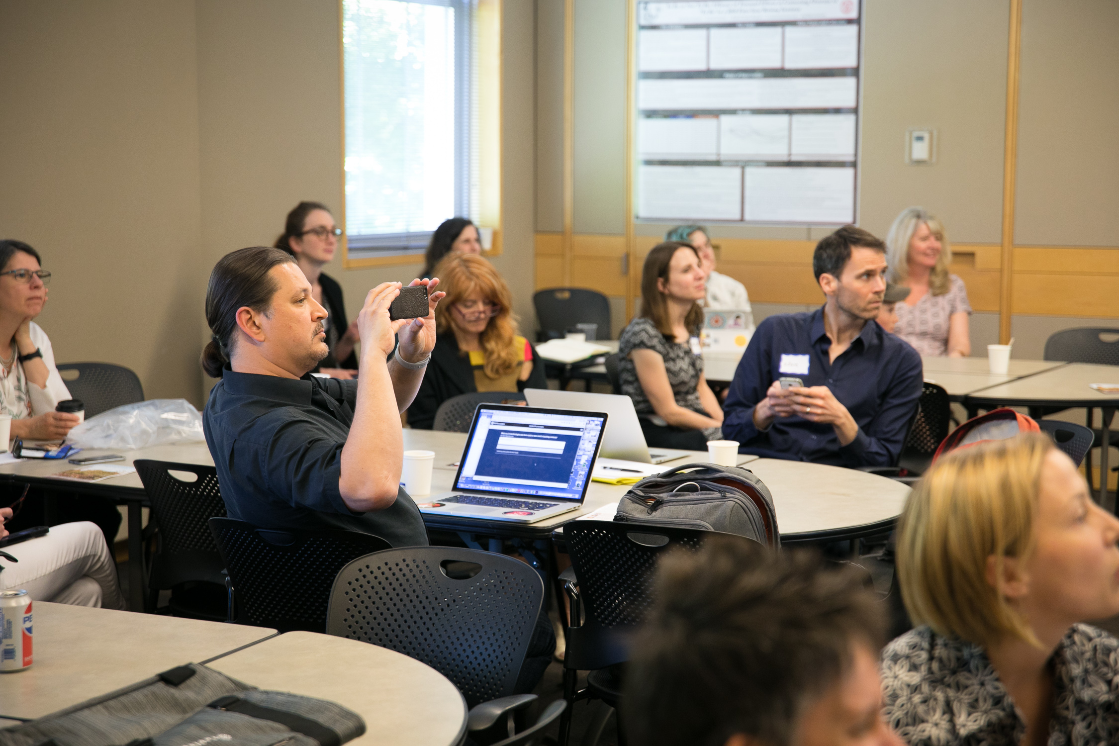 Mark Sarvary snaps a photo of a presentation while sitting at a laptop at a conference in 2018