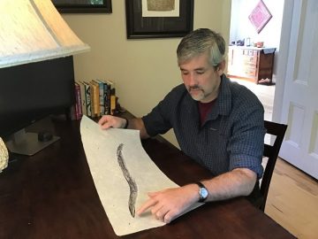 John Wyatt Greenlee looking at a print of an eel
