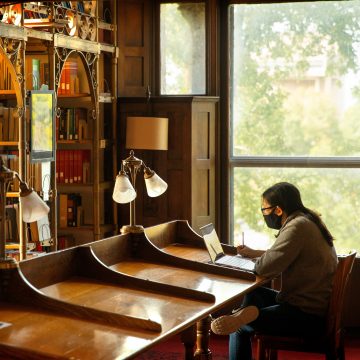 Student in a mask working in a library