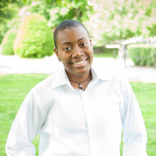 D-L Stewart, University of Denver smiling outside in a white button-up shirt