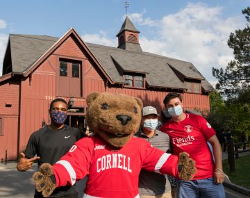 Three students pose with Touchdown in front of the Big Red Barn