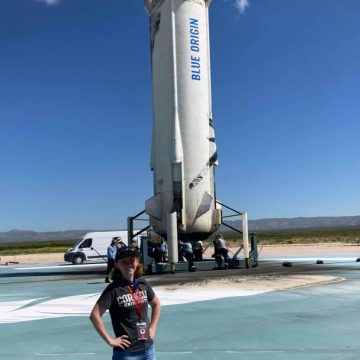 Morgan Irons stands in front of a Blue Origin rocket