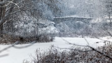 Snow falls around Beebe Lake, coating the bridge
