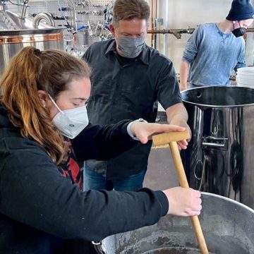 Graduate student Margaux Mora, front, Derek Edinger ’94 of Brewery Ardennes, and graduate student Andre Kalenak start the process of making Big Red Cranberry Sour ale.