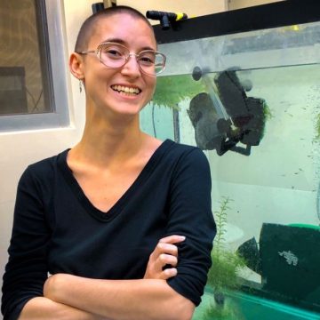 Rose Tatarsky stands in front of a tank filled with water and submerged equipment