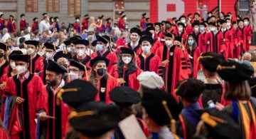 Doctoral candidates in red and black regalia process into the Ph.D. Hooding Ceremony during Cornell's 2022 Commencement weekend