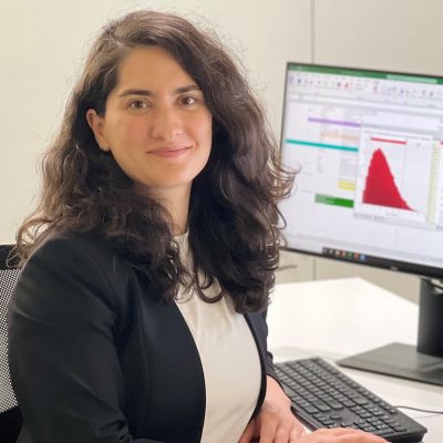 Ece Bulut sits in front of a computer displaying spreadsheets