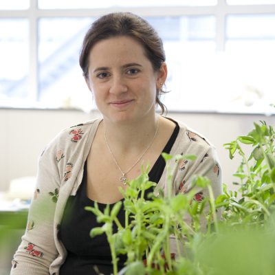 Melanie Smee stands with plants in the foreground