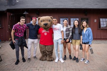 Graduate and professional students stand with Touchdown at the Big Red Barn during a TGIF