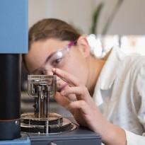 A woman in a white lab coat works with a piece of lab equipment