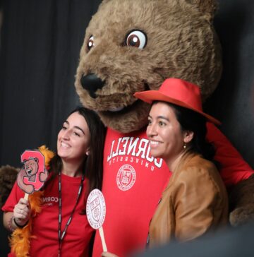 Two prospective students posing for a picture with a Cornell mascot, the bear, at Consider Cornell Experience, 2022
