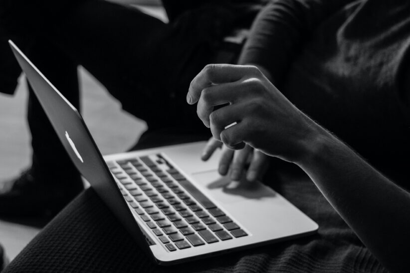 A woman's hands hover over a MacBook
