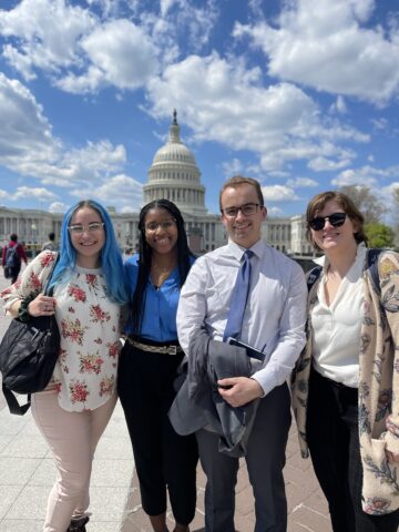 Four Cornell doctoral candidates in front of the Capitol building.