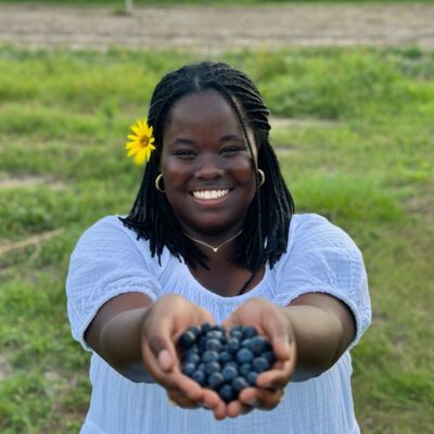 Faith Twinamaani holds out a handful of grapes