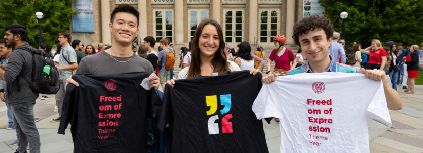 Three students hold up Freedom of Expression Theme Year t-shirts on Bailey Plaza at the Dean's Welcome