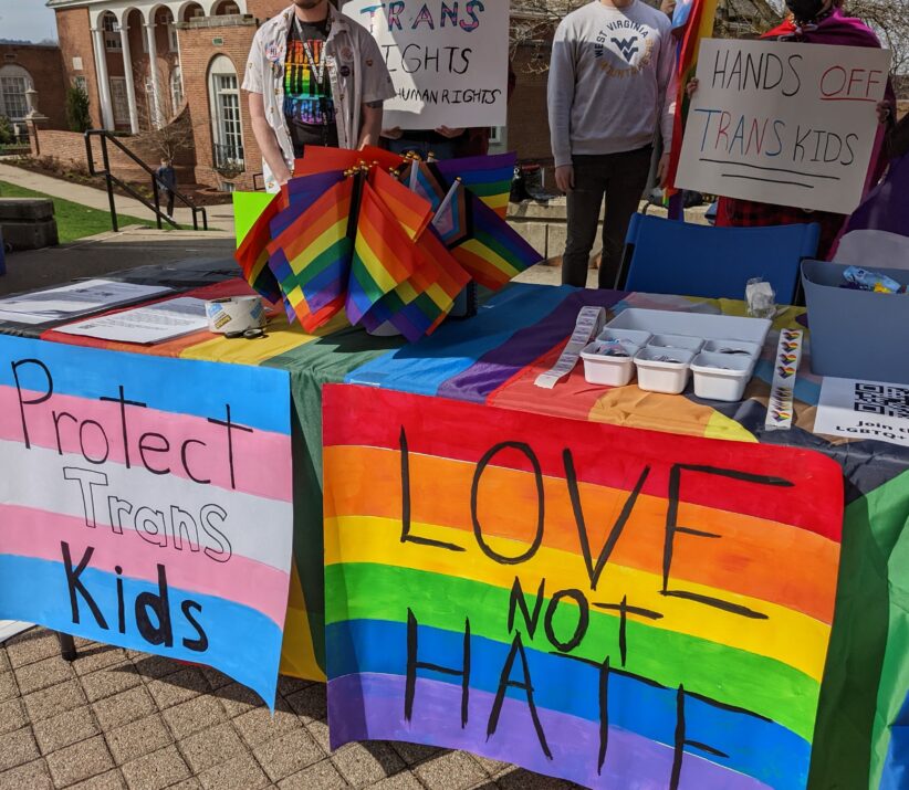 Tables with banners reading, 'Protect trans kids' and 'Love not hate'