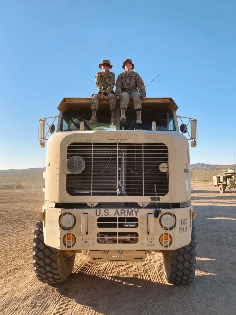 Two members of the military sit on a U.S. Army truck