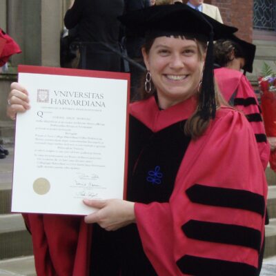 Corrie Moreau in doctoral regalia holding her diploma