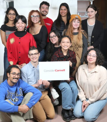 A group of Participants from 2023 Consider Cornell: Experience holding a Consider Cornell sign.