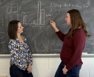 Natasha Holmes and Rebeckah Fussell work on a blackboard