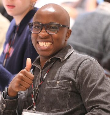 A male facing the camera with a smile and giving a thumbs up.