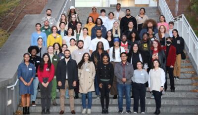 Fifty students pose for a formal photo on a set of outdoor stairs