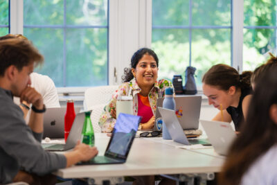 Students sit around a table with laptops in front of them