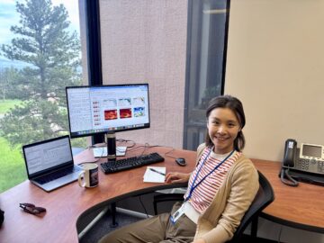Yan-Ning Kuo sits at a desk in front of a laptop and a monitor