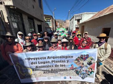 A group of individuals stand behind a banner during a parade
