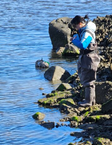 Yuqing Chen stands on rocks next to a body of water