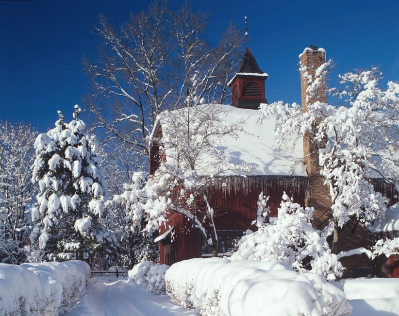 The Big Red Barn Graduate and Professional Student Center and the surrounding trees and bushes covered with snow