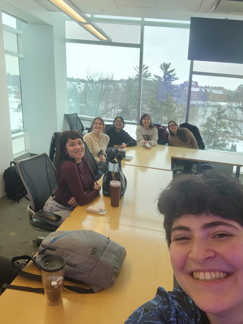 Rikki Laser takes a selfie with students seated around the table behind her