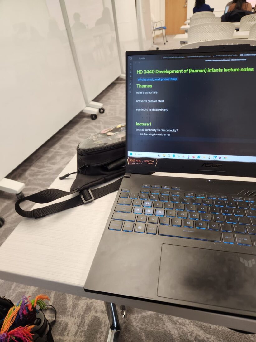 A laptop sits open on a table with lecture notes on the screen