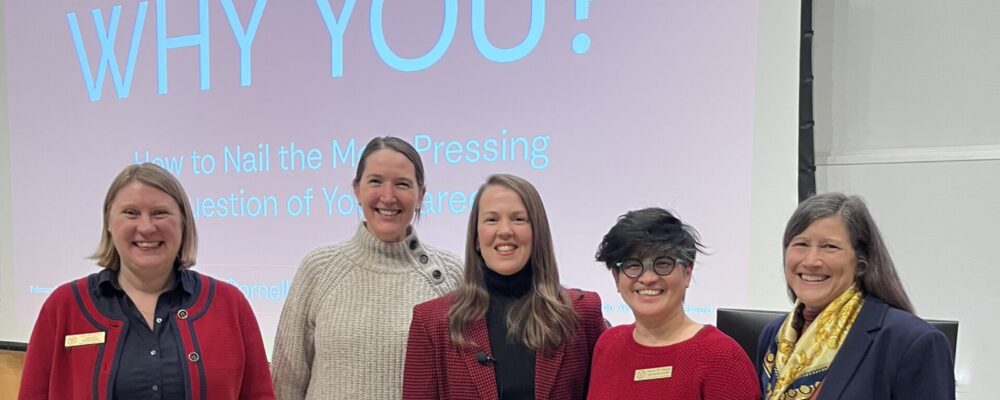 Group of people in front of a podium and slide reading "Why You?"