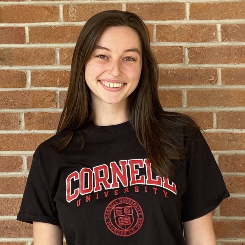 Pia Spychalla wears a Cornell University t-shirt and stands against a brick wall