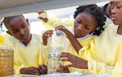Students work on a science experiment, pouring liquid into a jar