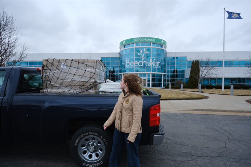A student stands in front of a loaded truck parked in front of the Beech-Nut building