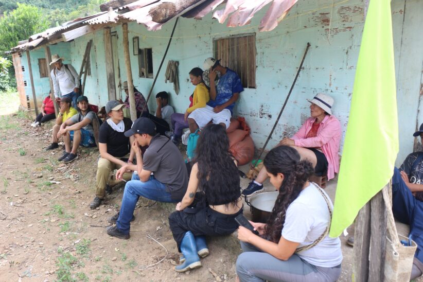 A group of people sit outside a structure