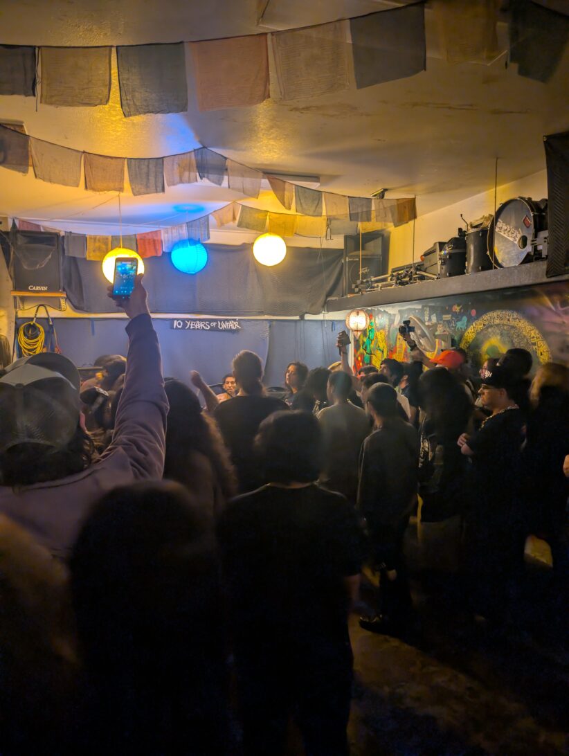 A crowd gathers in front of a stage where punk musicians are playing