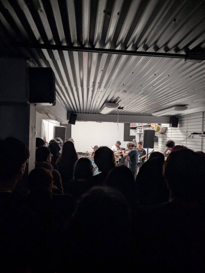 A crowd gathers in front of a stage where punk musicians are playing