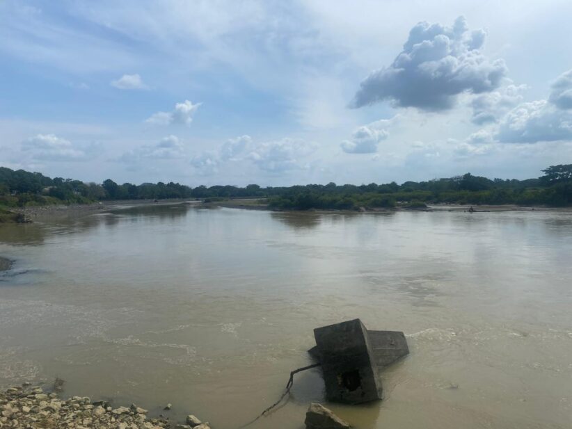 A body of water seen from theshore with a large piece of concrete in the shallow water