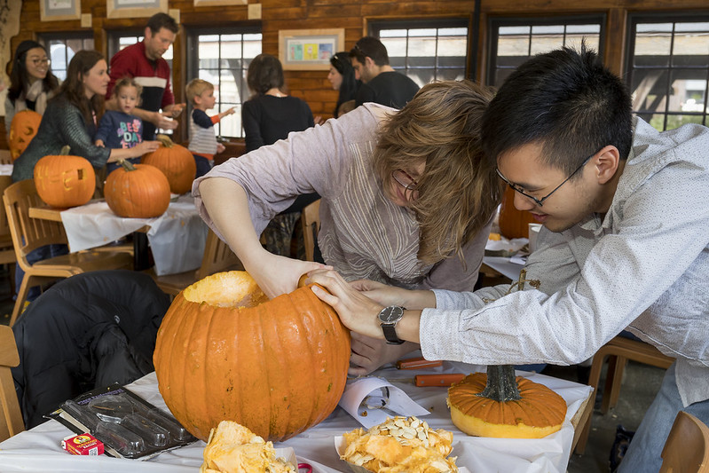Students and their families carve pumpkins at the Barn