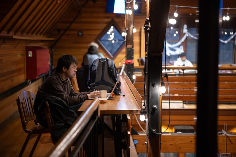 A student works on a laptop on the upper floor of the Barn